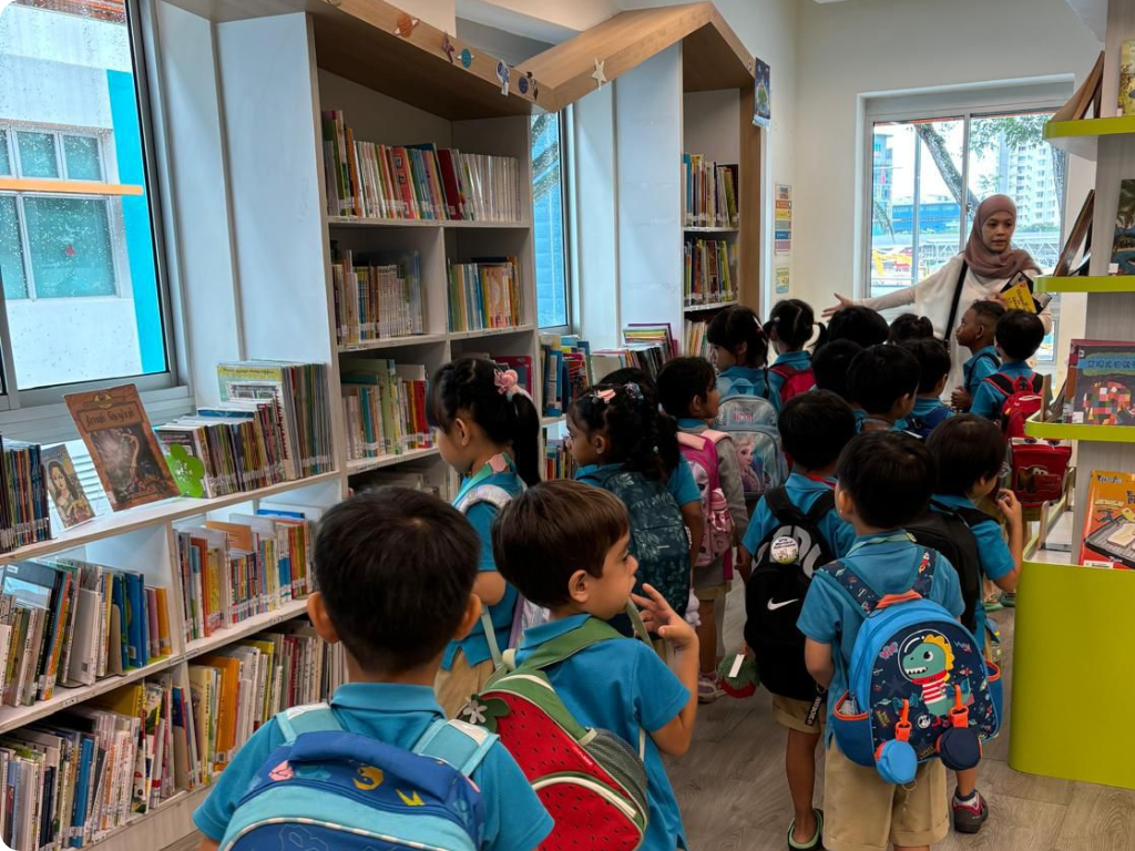 MOE Kindergarten children explore the library at Pei Tong Primary School, discovering a wide variety of books during a guided visit.